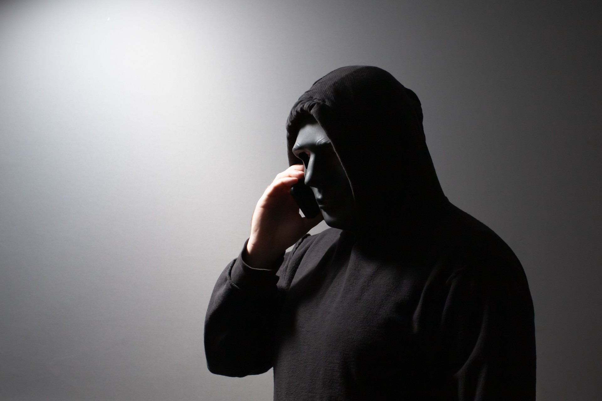 Phone Scammers, man in a mask with a phone, cyber criminal stealing information, hacker attacking accounts, online theft and fraud